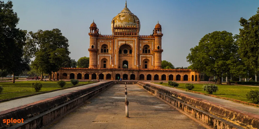 Domed Mughal-style mausoleum framed by a garden pathway and green lawns