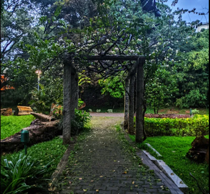 Stone pergola over a paved pathway lined with greenery in Sadashivnagar Park