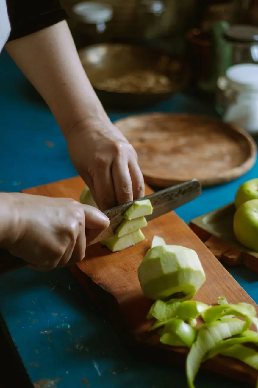 Hands washing and cutting an apple in a kitchen