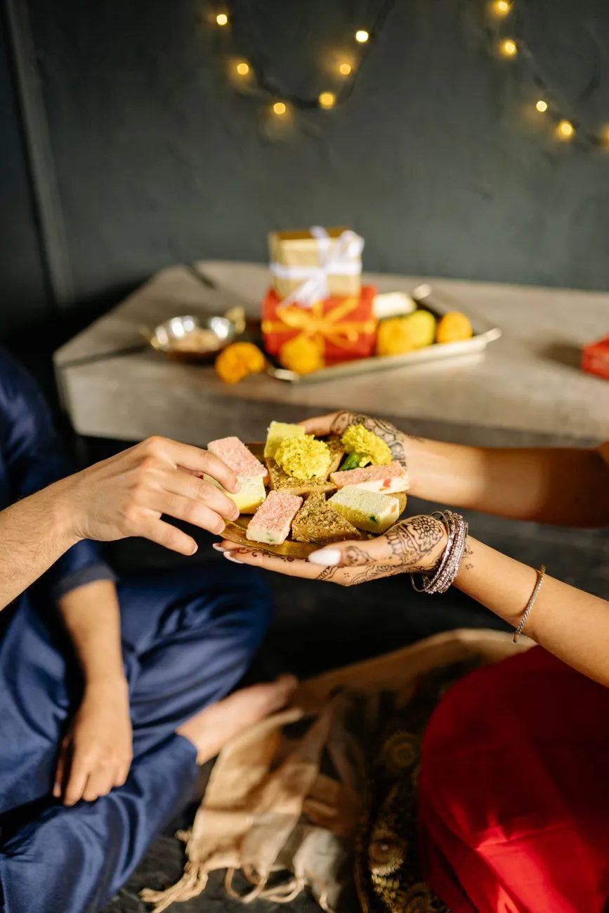 People sharing traditional sweets from a platter