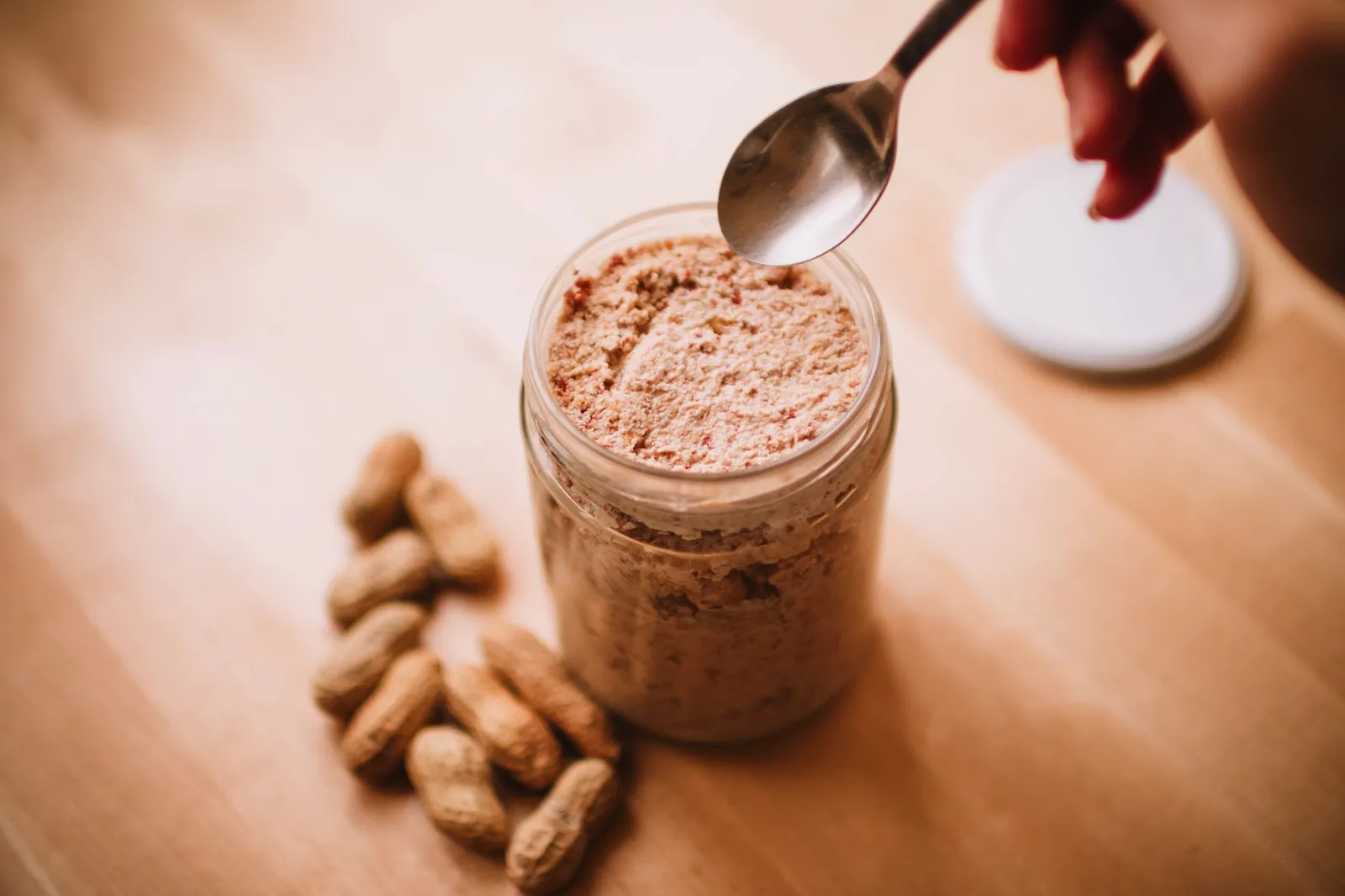 Open jar of peanut butter with a spoon