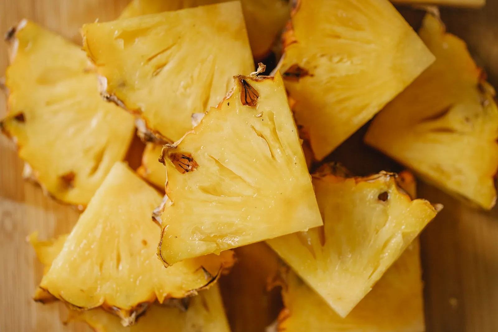 Bite-sized pineapple chunks on a wooden surface