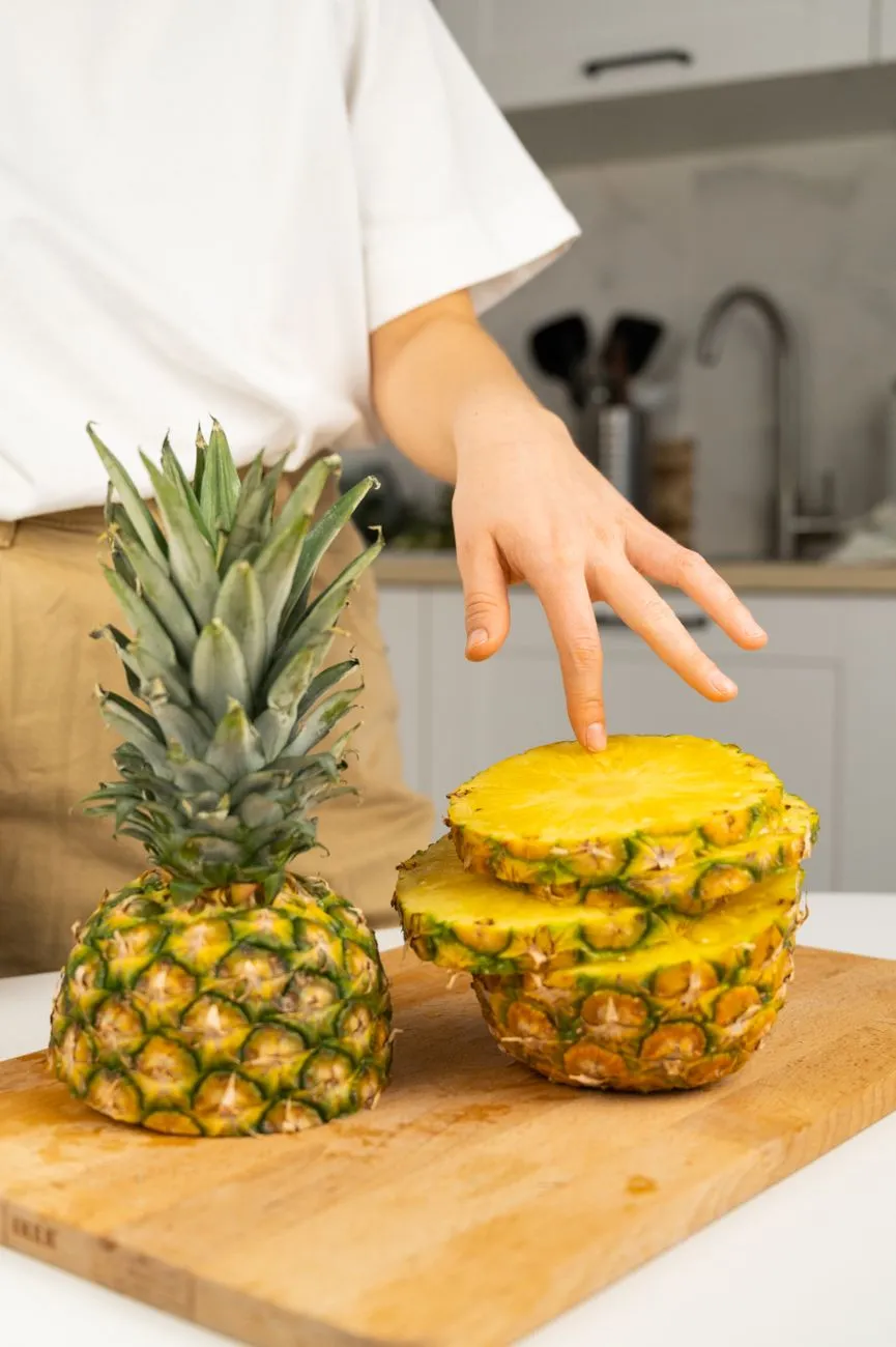 Hands preparing pineapple flesh on a cutting board