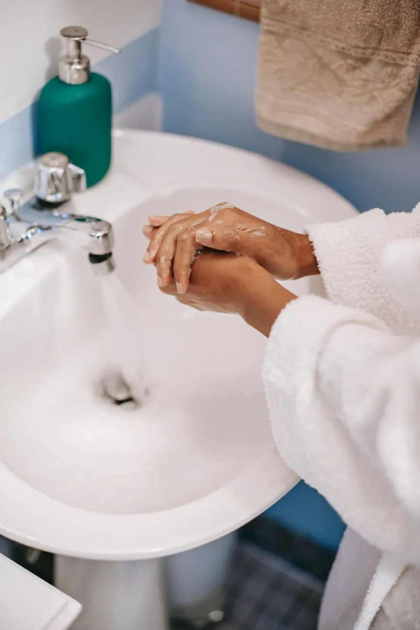 Washing hands thoroughly with soap under running water