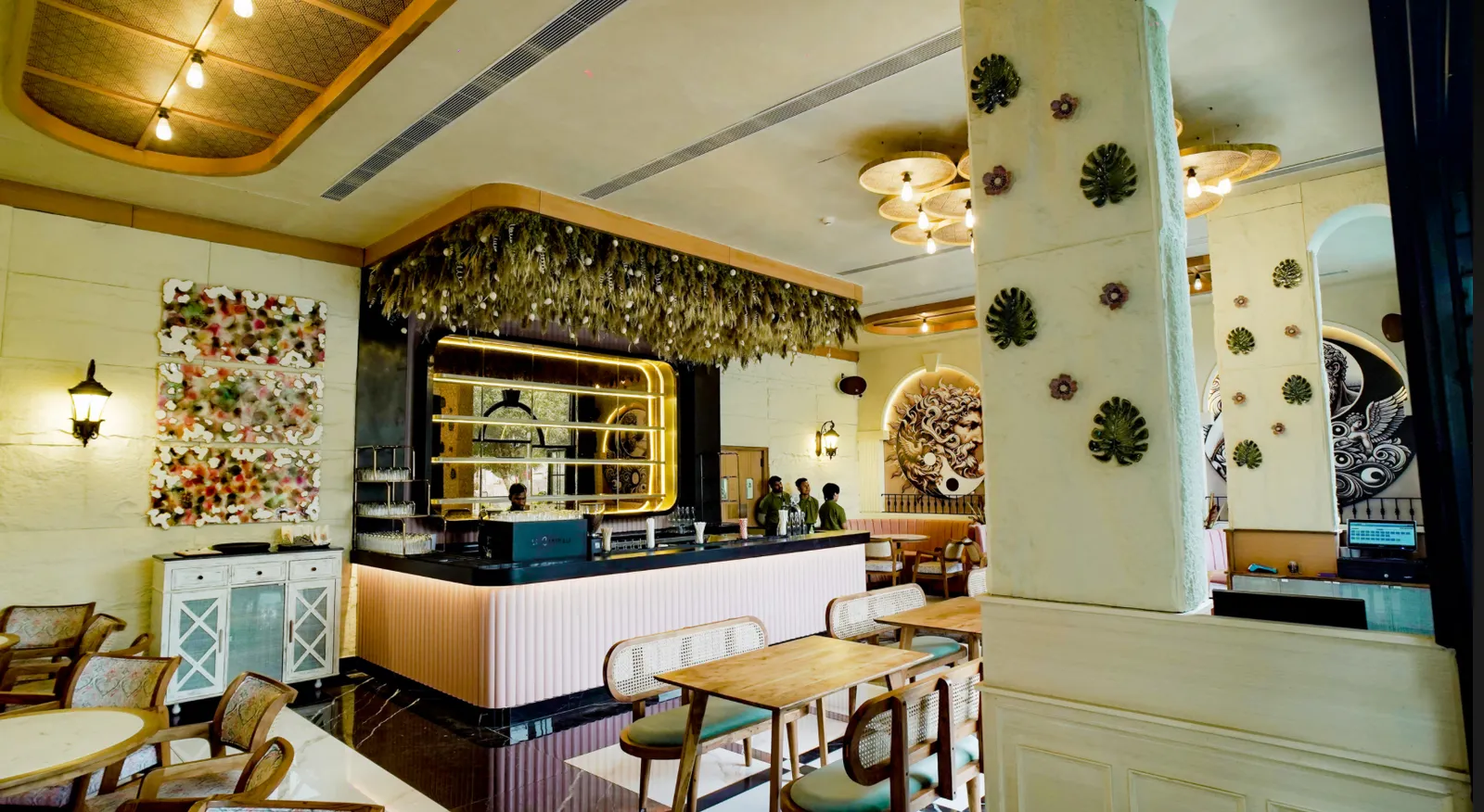 Pastel pink cafe counter with hanging greenery and wooden dining tables indoors