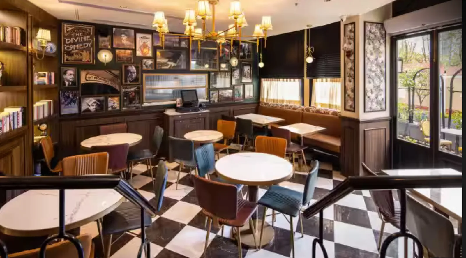 Cafe dining area with a checkered floor, framed art gallery wall and brass chandelier