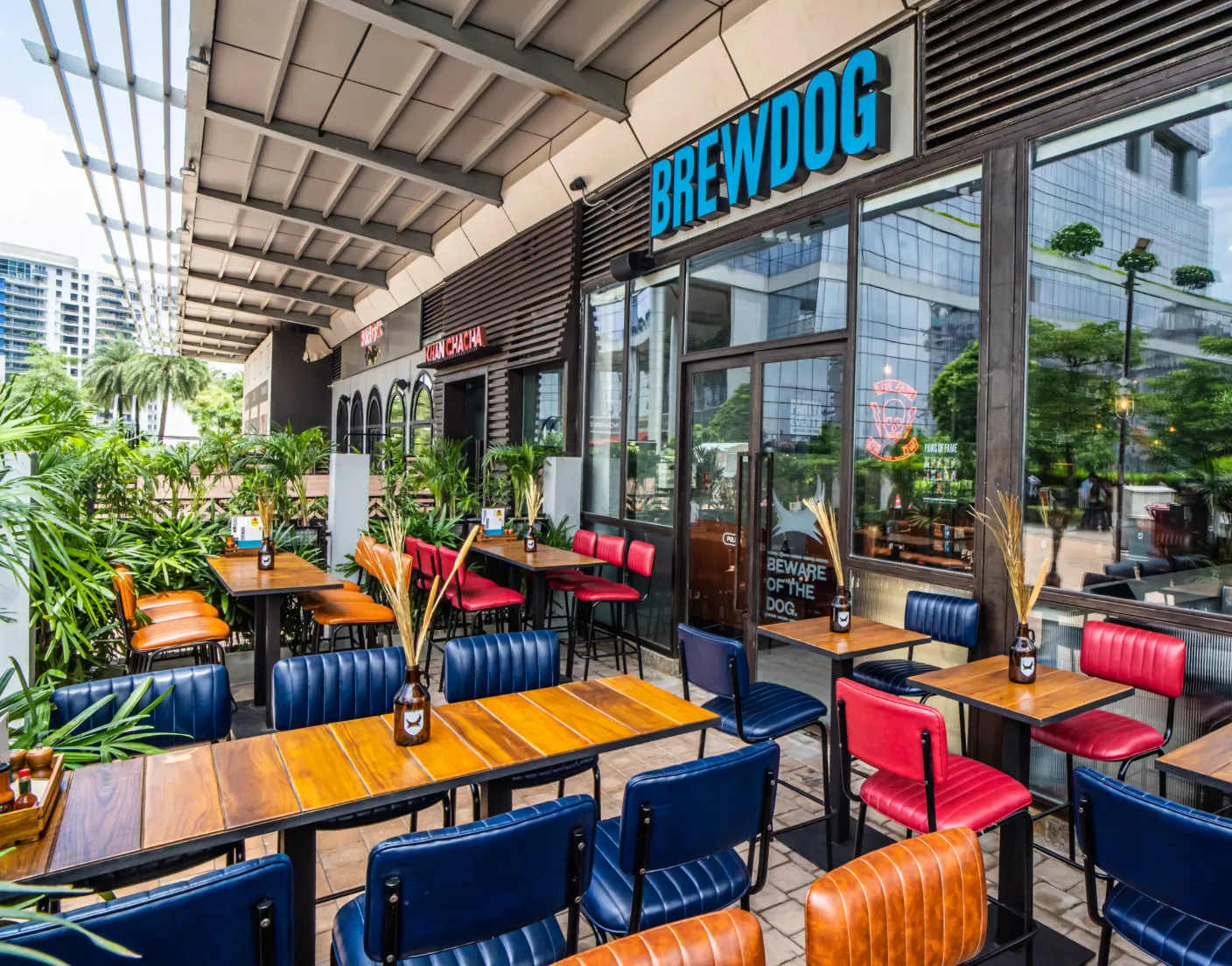 Brewdog cafe patio with colourful chairs beneath a lit signboard and neon dog sign