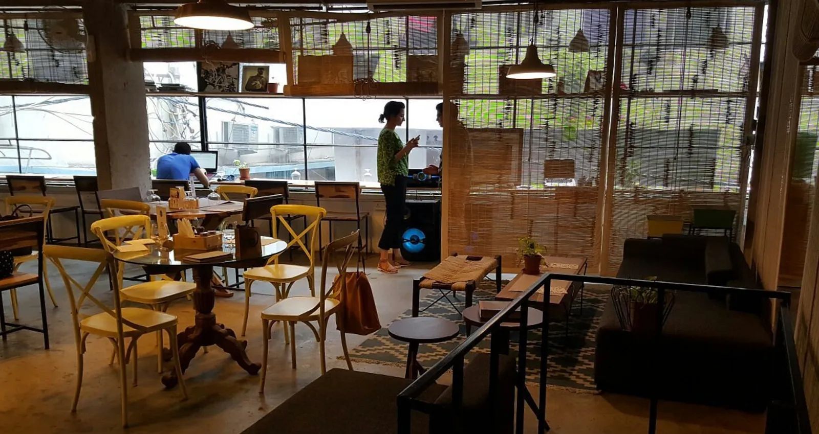 Loft-style cafe interior with woven bamboo blinds, wooden furniture and people chatting