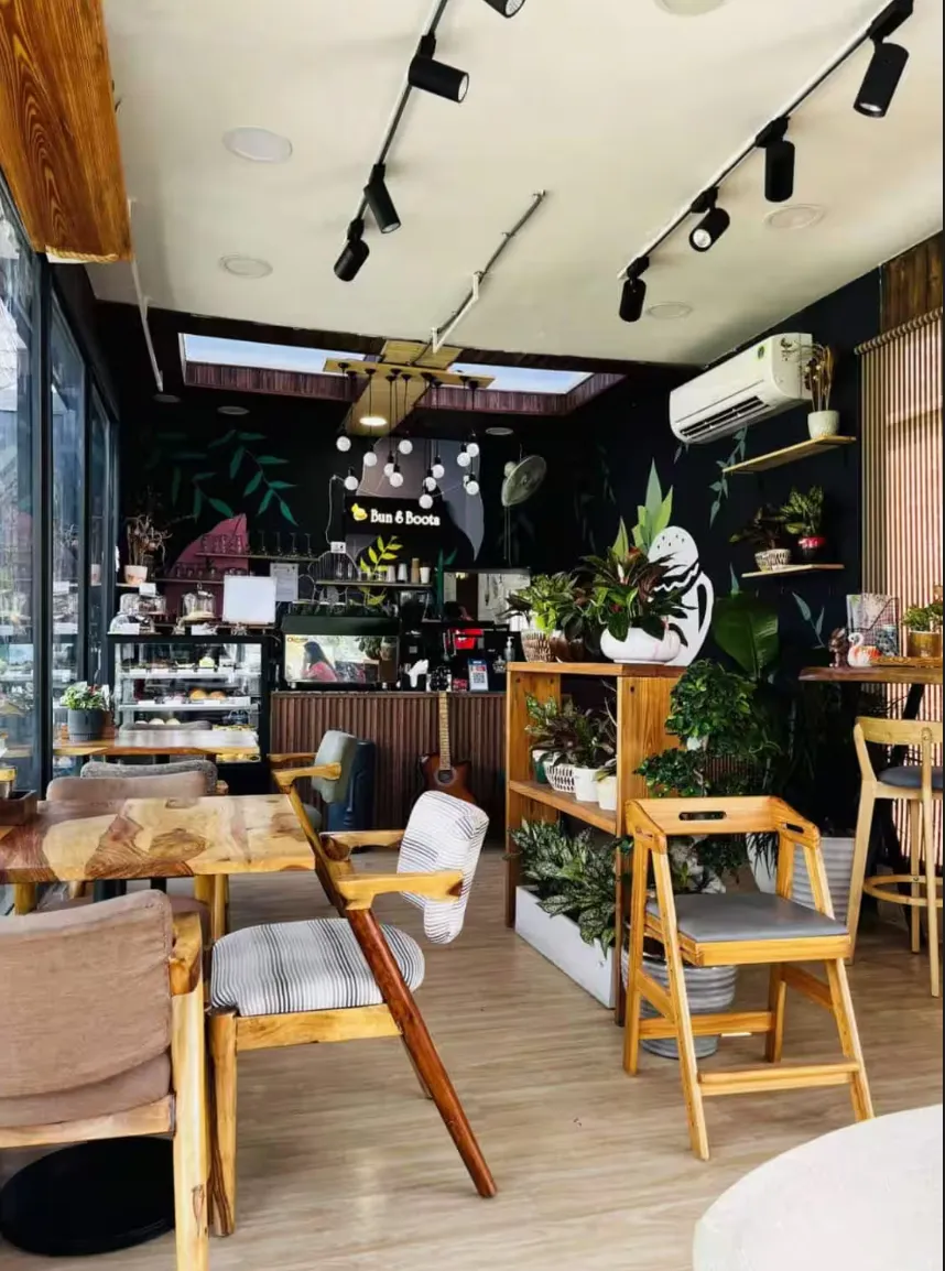 Plant-filled cafe interior with wooden chairs, a guitar and hanging light fixtures