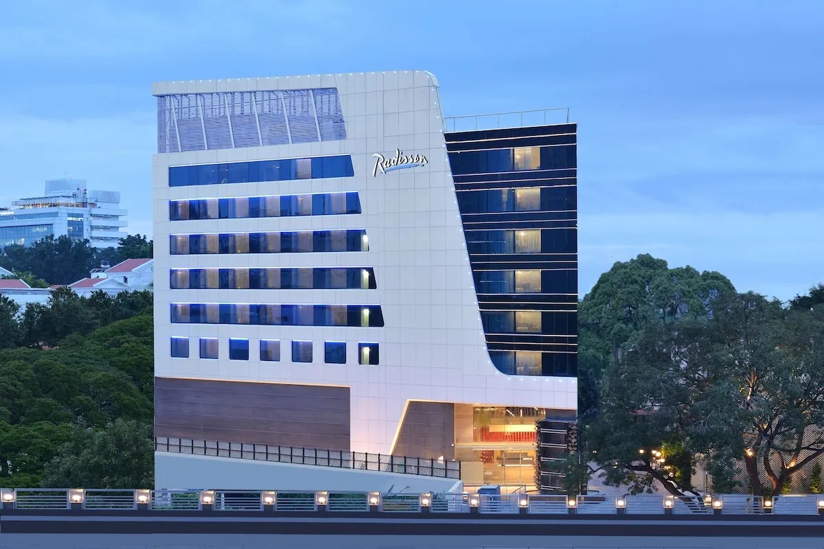 Radisson hotel exterior lit up at dusk with a multi-storey glass facade