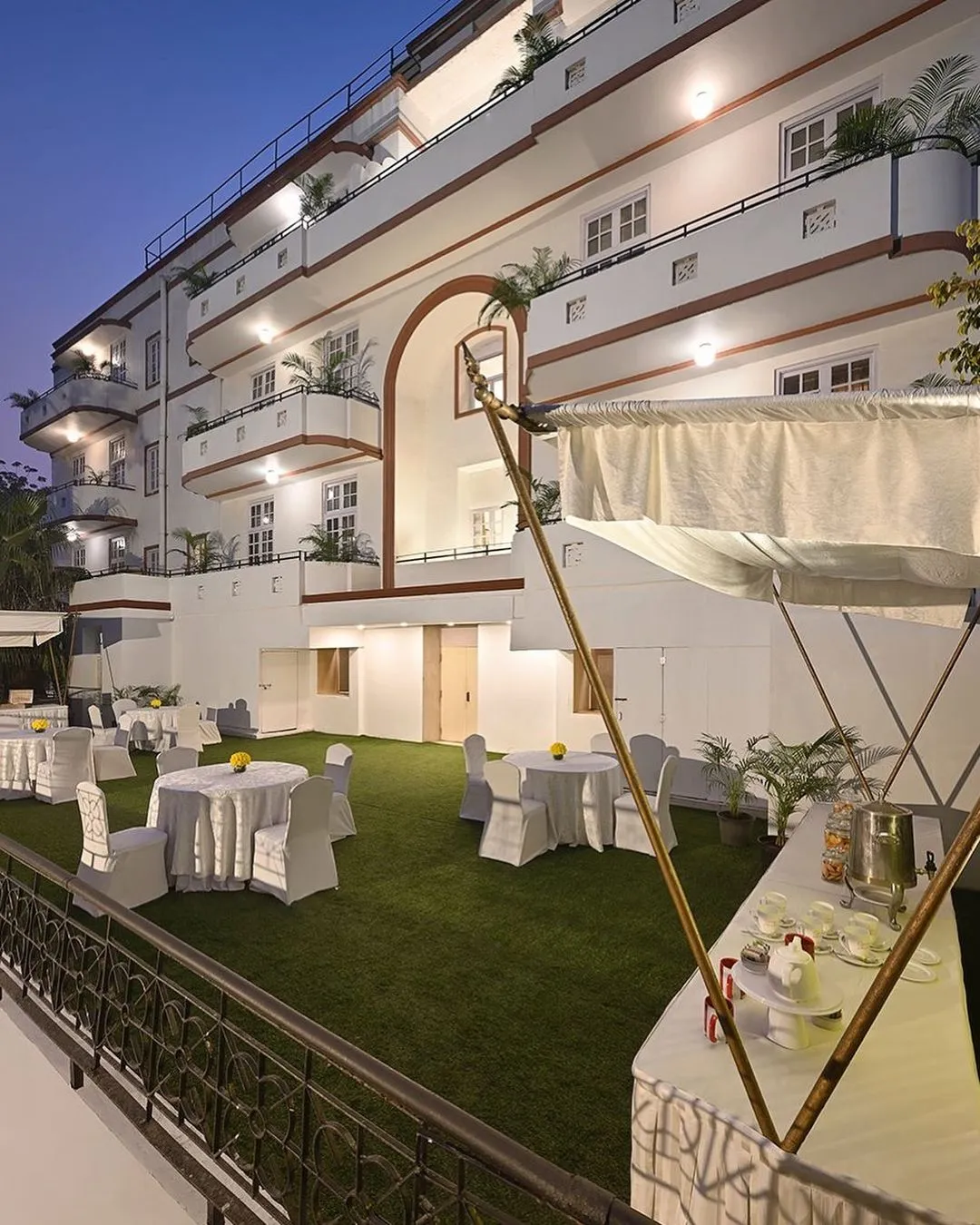 White heritage hotel courtyard set up with round tables and a canopy at dusk