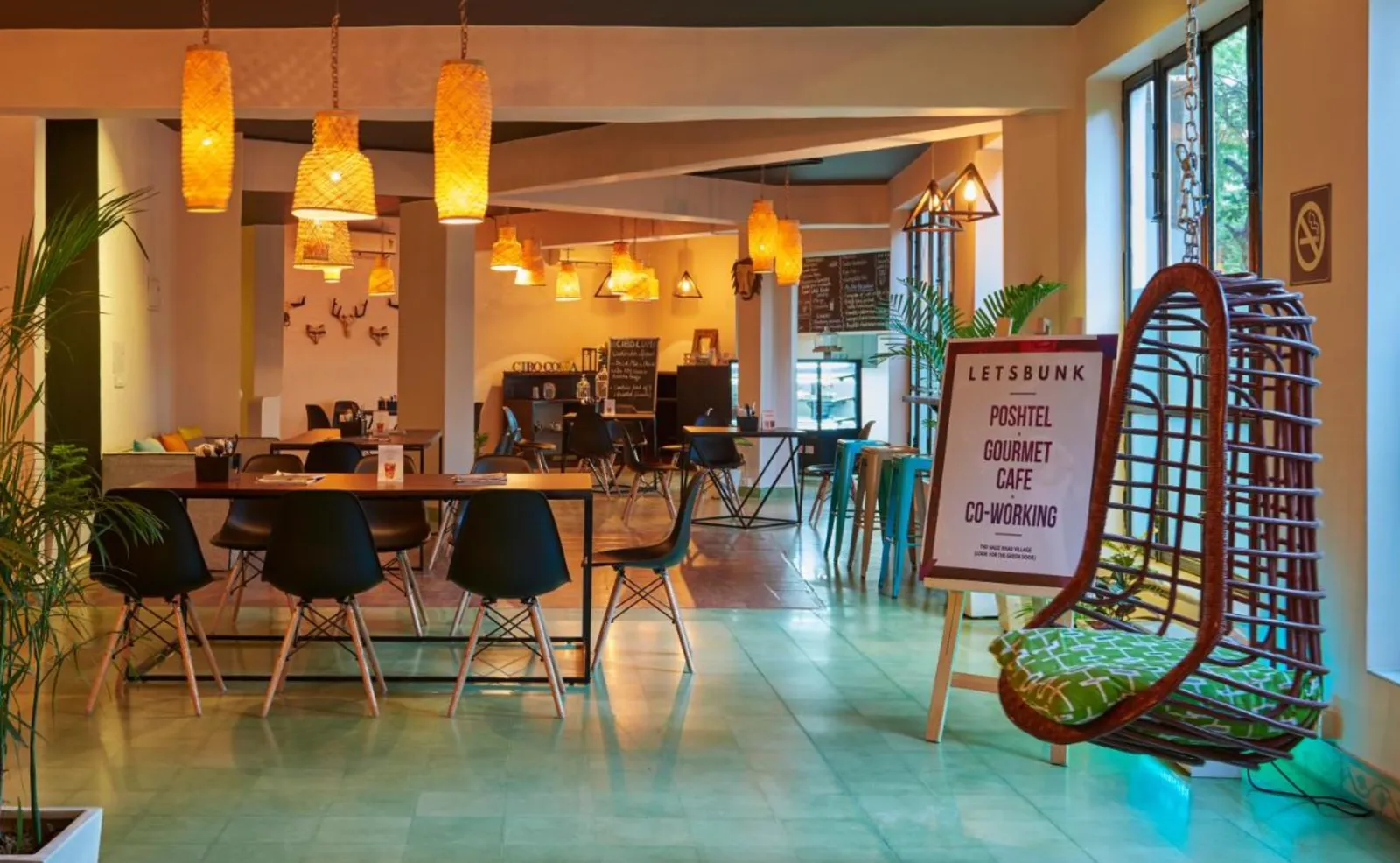 Cafe and co-working space with hanging lamps and a Letsbunk Poshtel signage board