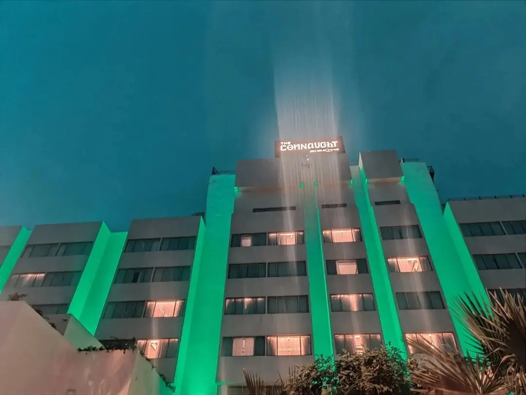 The Connaught hotel building lit green with signage against a night sky