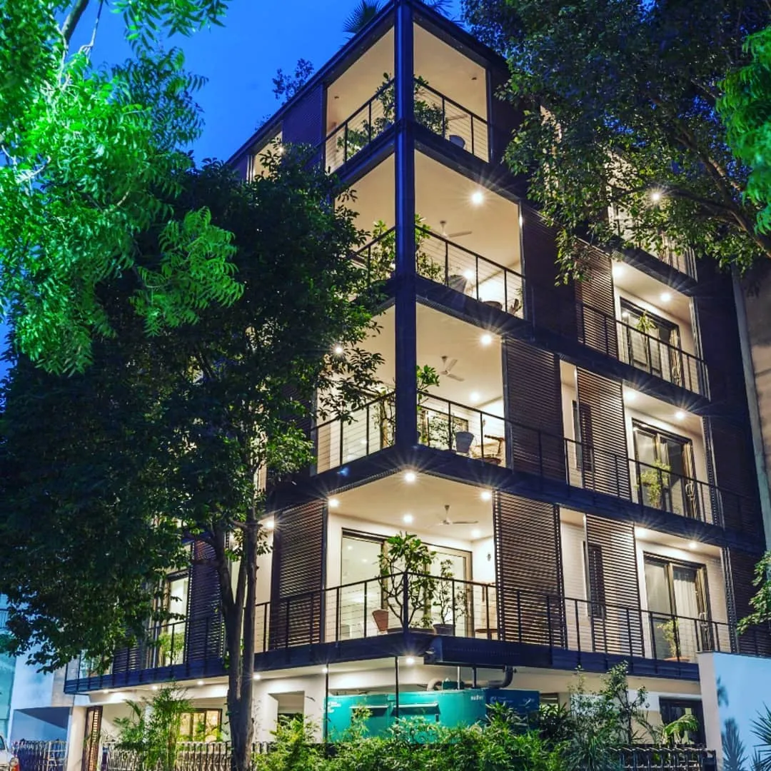 Multi-storey building facade with balconies and potted plants lit at night