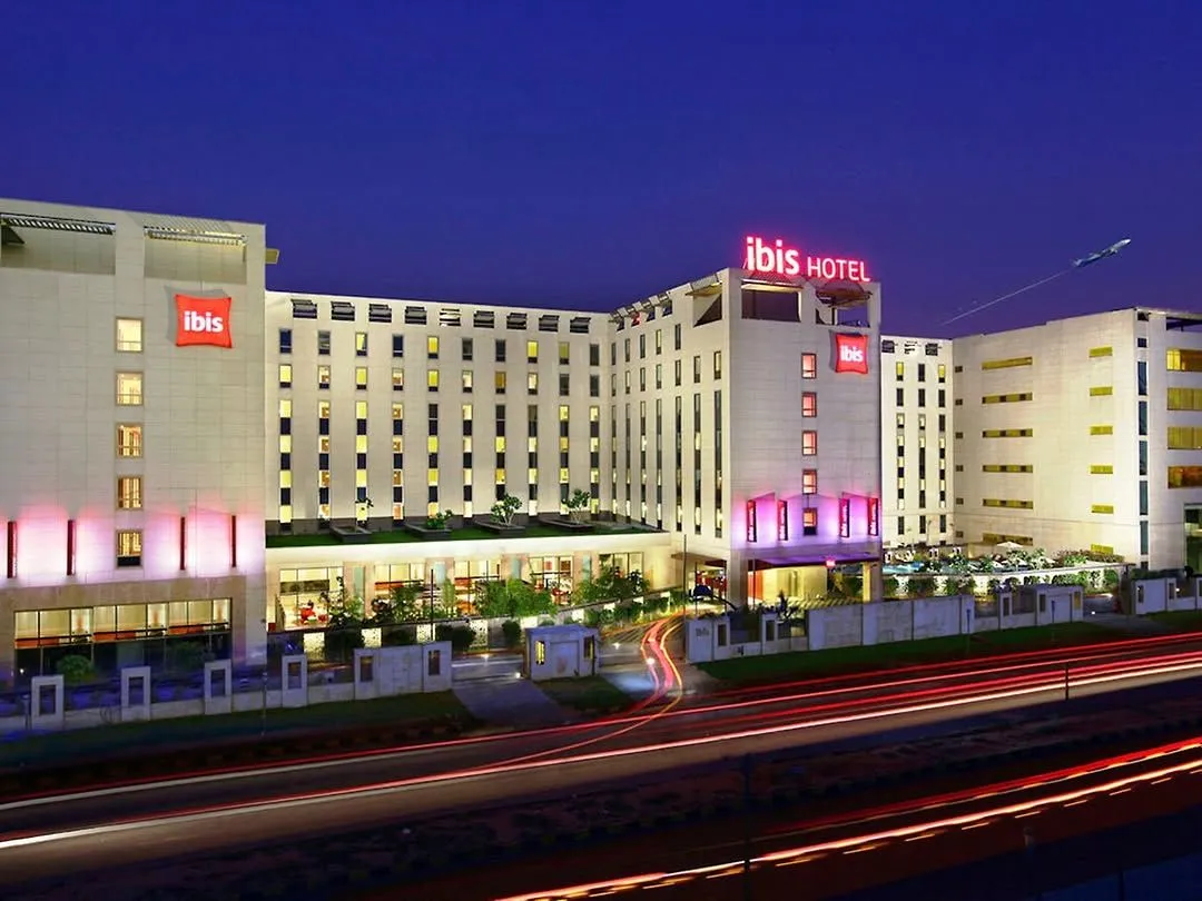 Ibis Hotel exterior lit up at night beside a road with light trails
