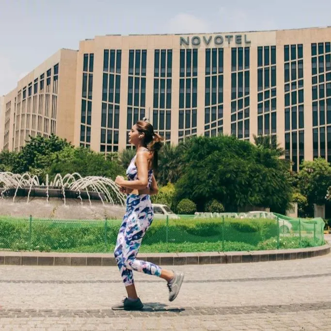Woman jogging past a fountain with the Novotel building in the background