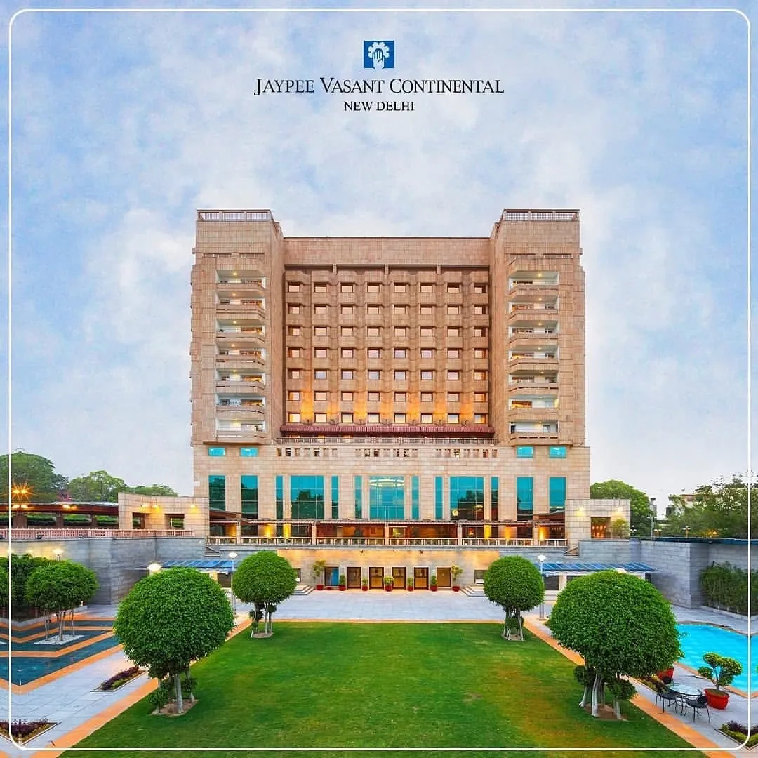 Jaypee Vasant Continental hotel facade with lawn, trees and a pool