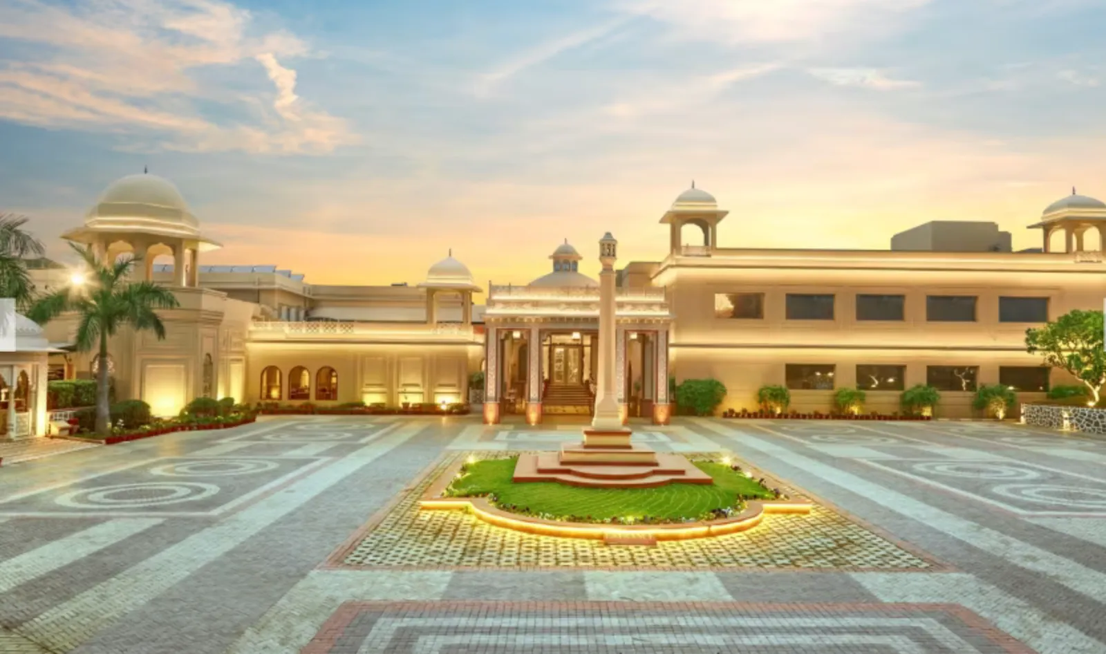 Grand domed resort building lit up at dusk with a circular garden driveway