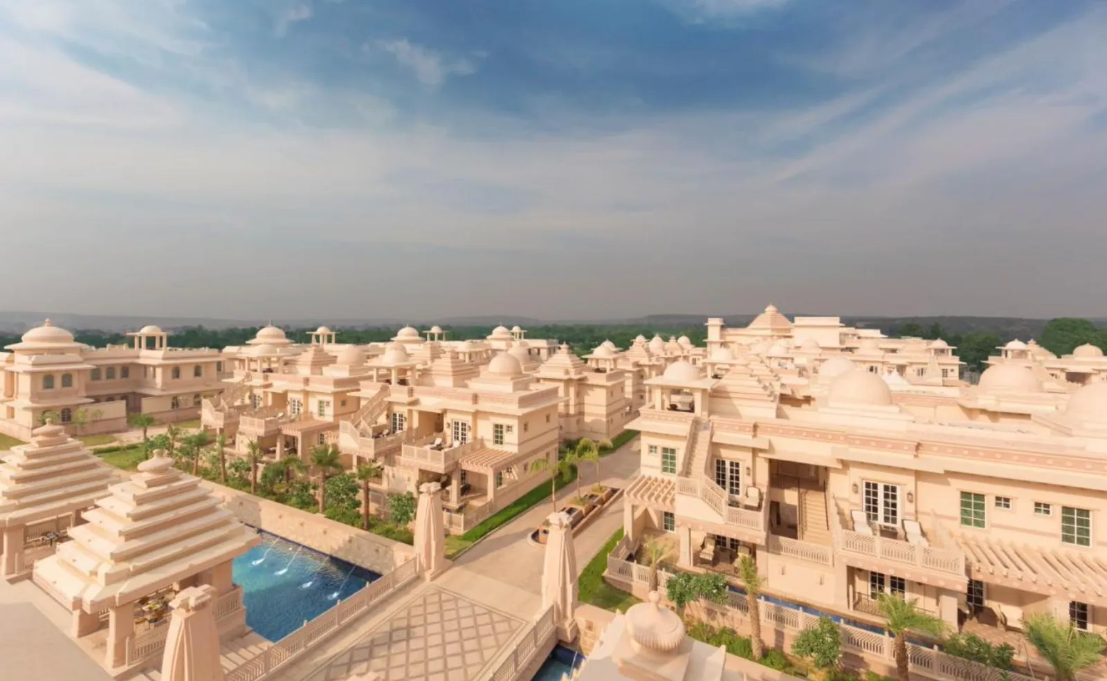 Aerial view of a domed palace-style resort complex with pools amid hazy hills