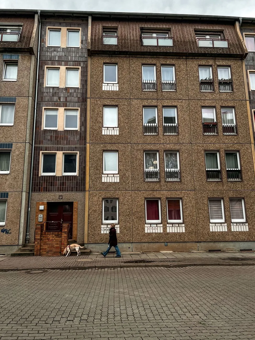 Dog walker leaving an apartment building with a dog on leash