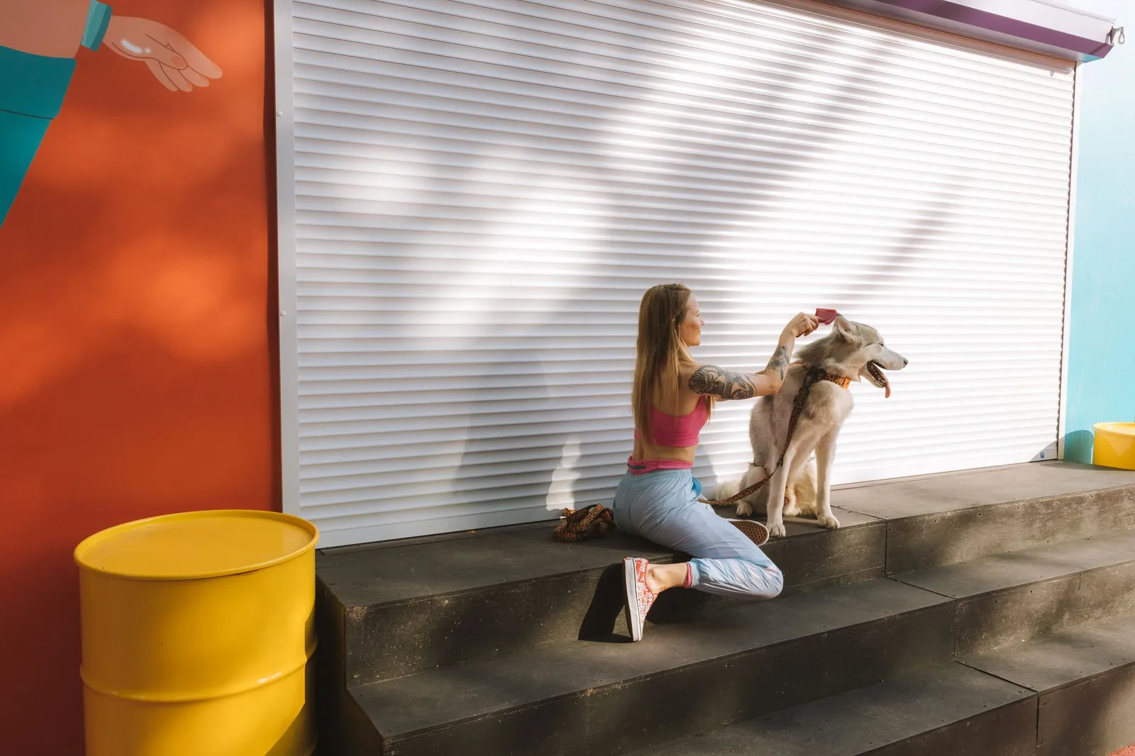Dog owner gently brushing a dog sitting on a bath mat before a home groom