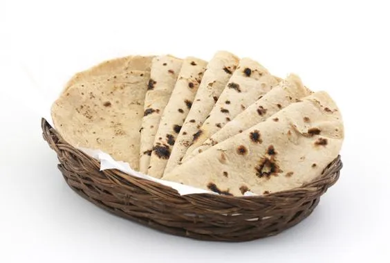 Stack of folded chapatis in a woven basket lined with tissue paper
