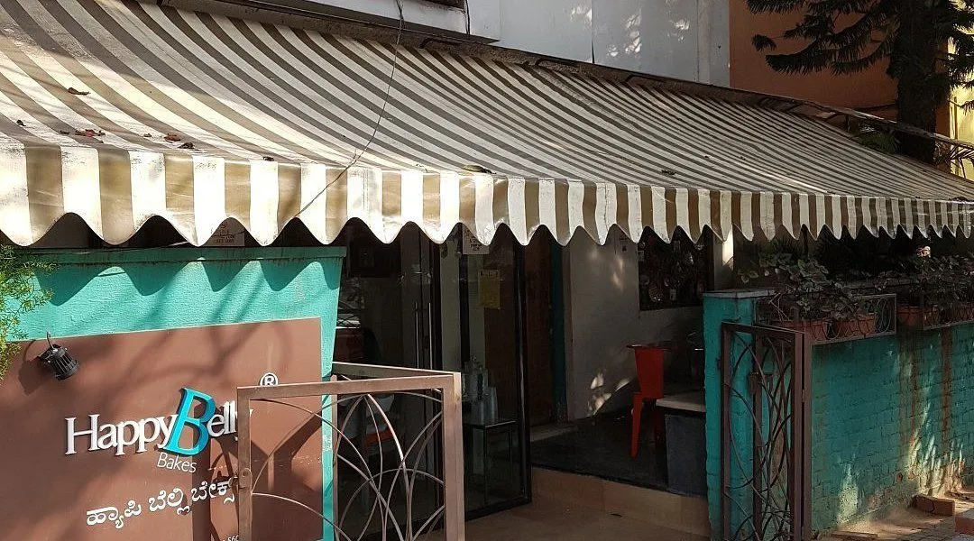 Striped awning and storefront entrance of Happy Belly Bakes