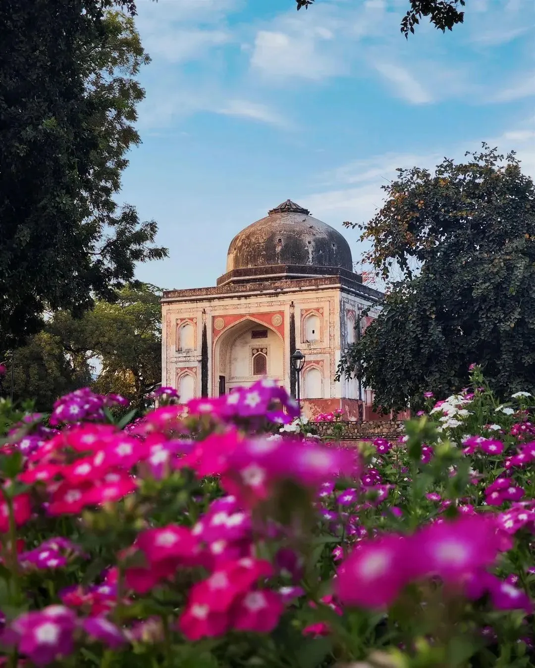 Domed heritage pavilion framed by pink and white flower beds