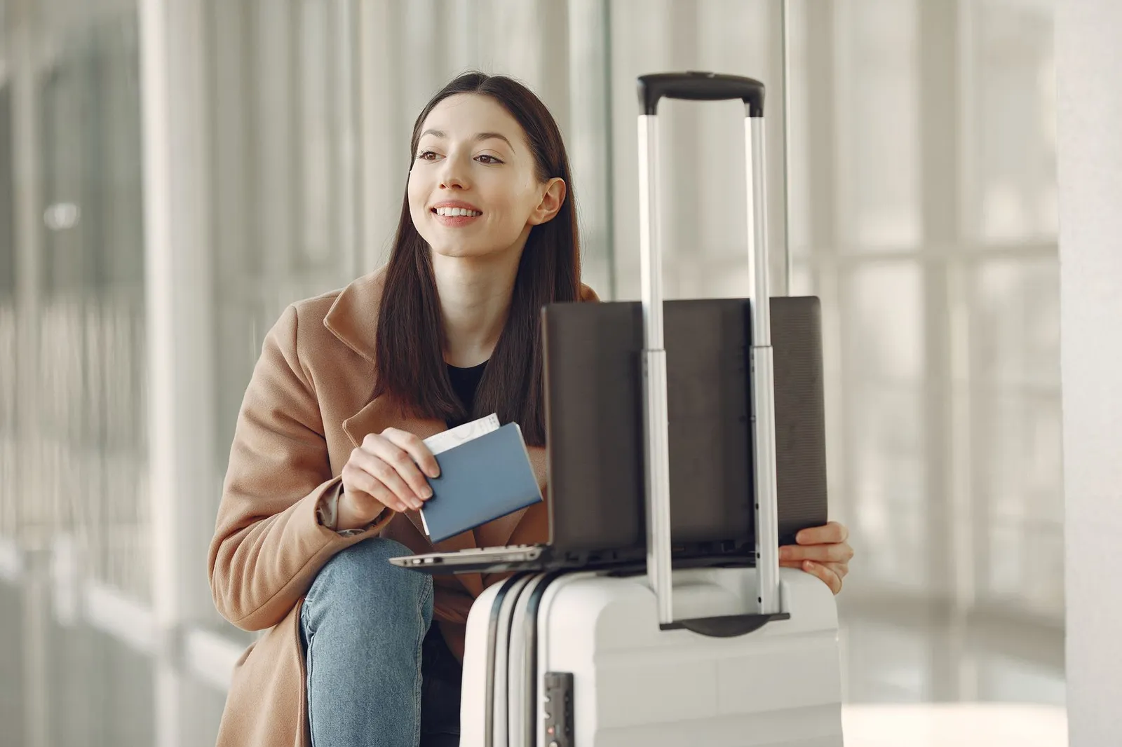 Traveller checking tickets on a laptop beside luggage